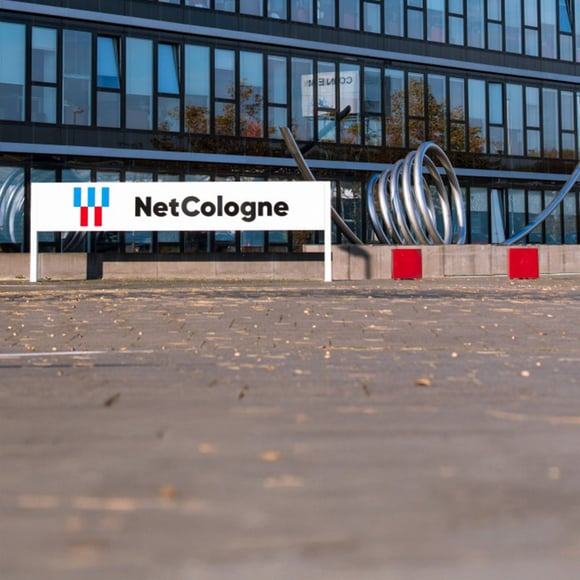 Vue extérieure du bâtiment de NetCologne avec son logo et son architecture moderne, un client de la solution de surveillance informatique d'USU.