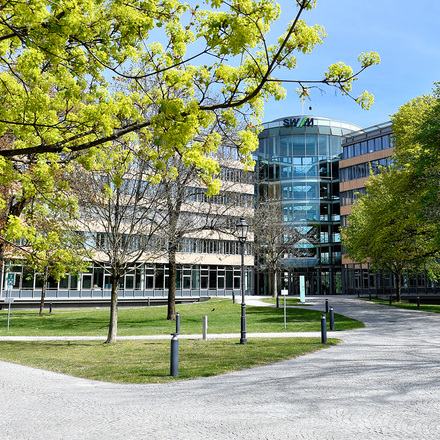 Exterior view of the Stadtwerke München (SWM) building, surrounded by green nature. SWM is a customer of the USU IT monitoring solution.