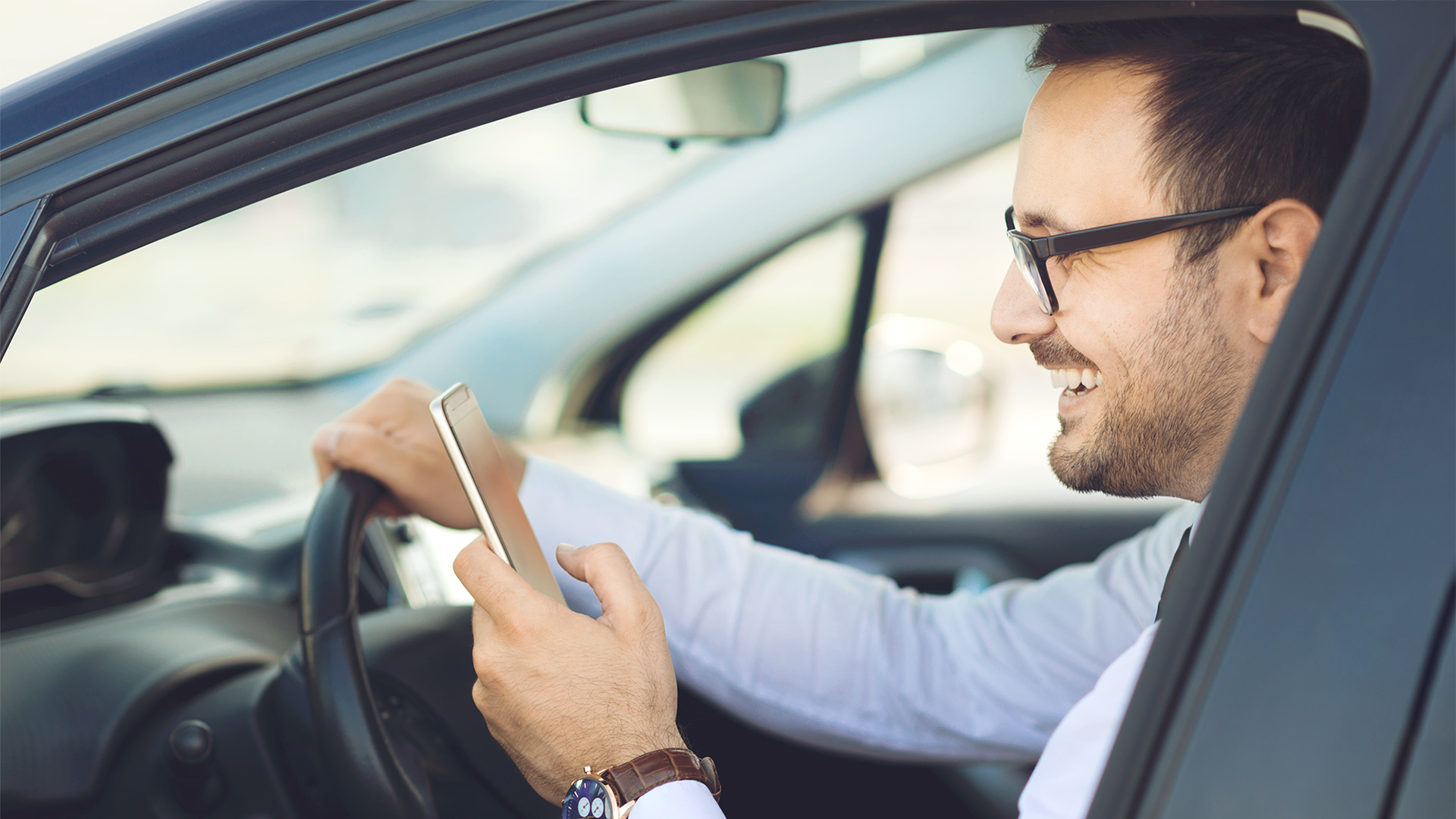 Mann mit Smartphone im Auto