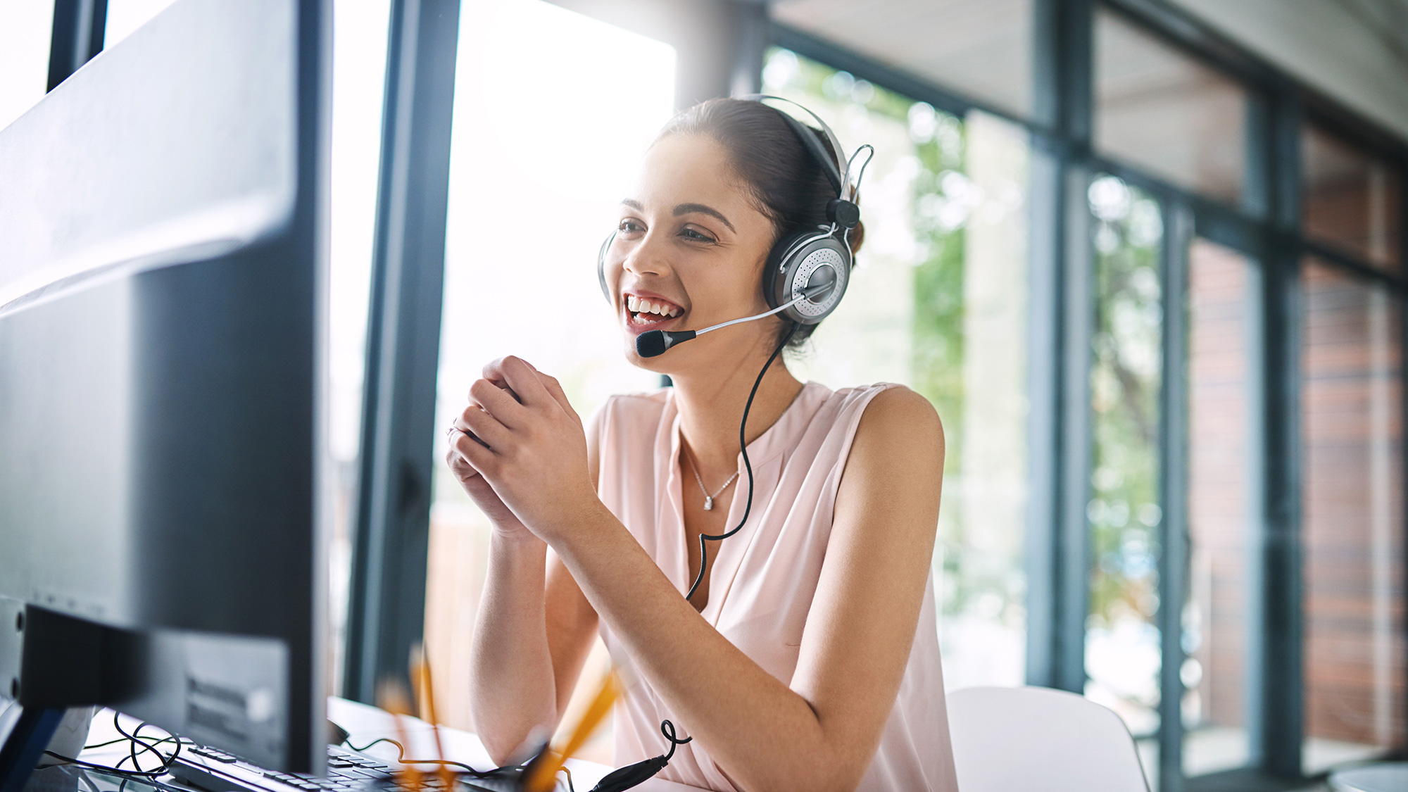 Frau mit Headset am Bildschirm