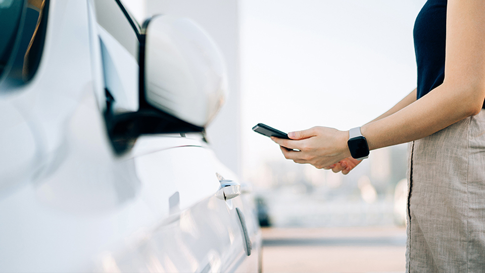 Frau mit Smartphone am Auto