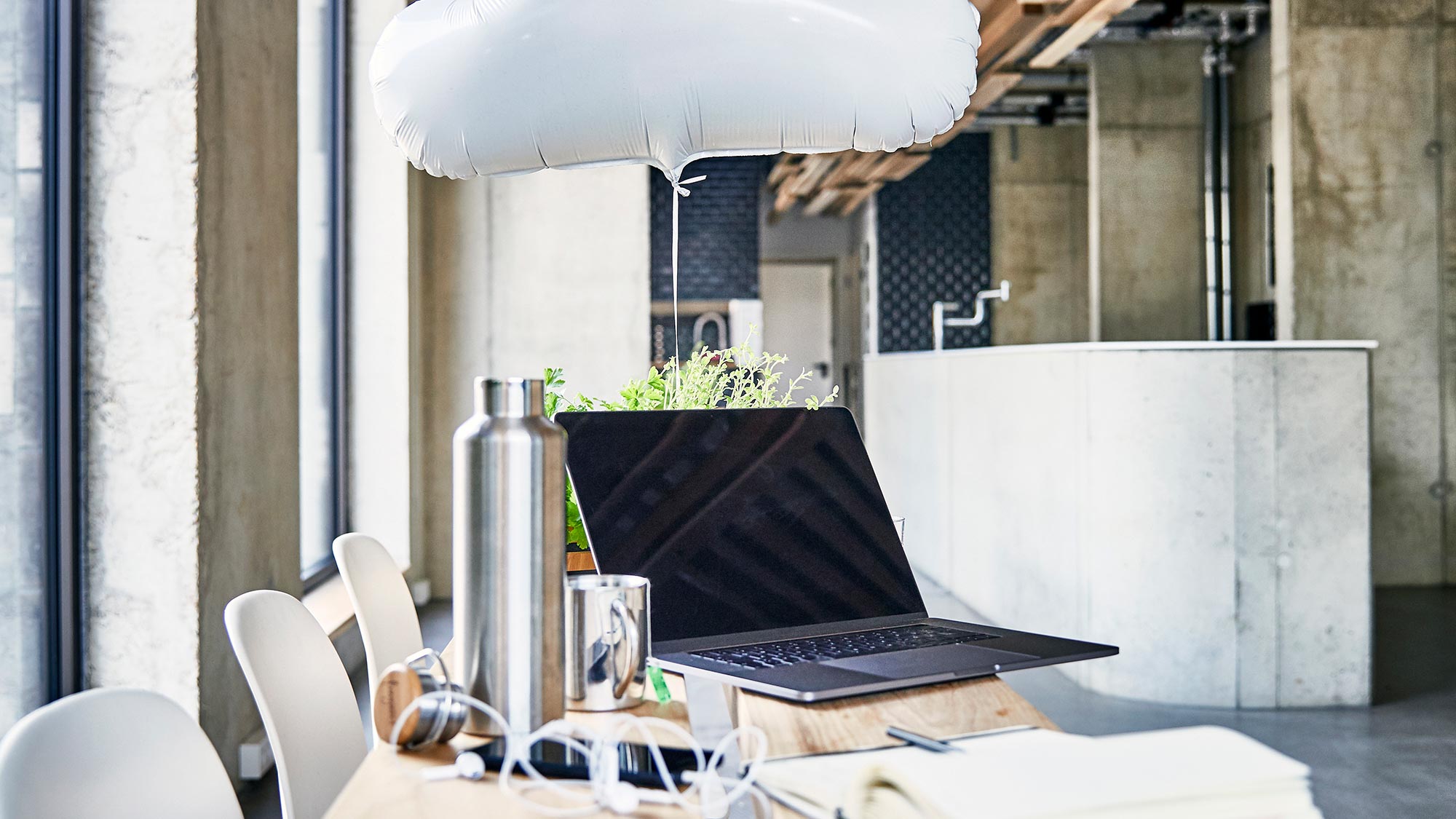Laptop turned off on a table with a white cloud balloon on it