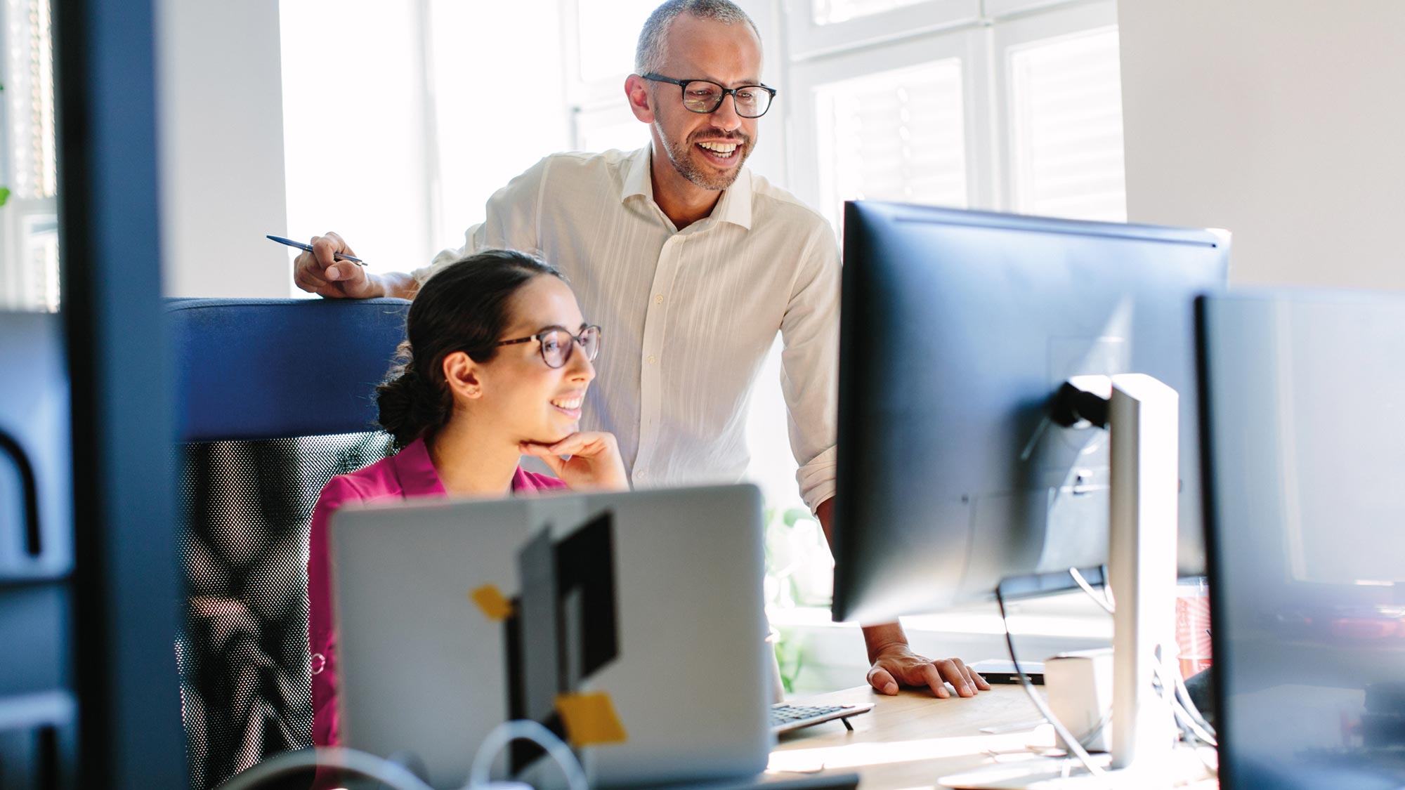 Man and woman working together looking at a computer monitor